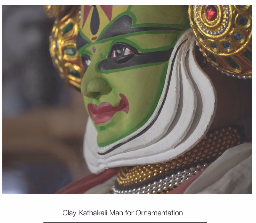 A clay Kathakali figure in full green and gold face paint, photographed on the site visit