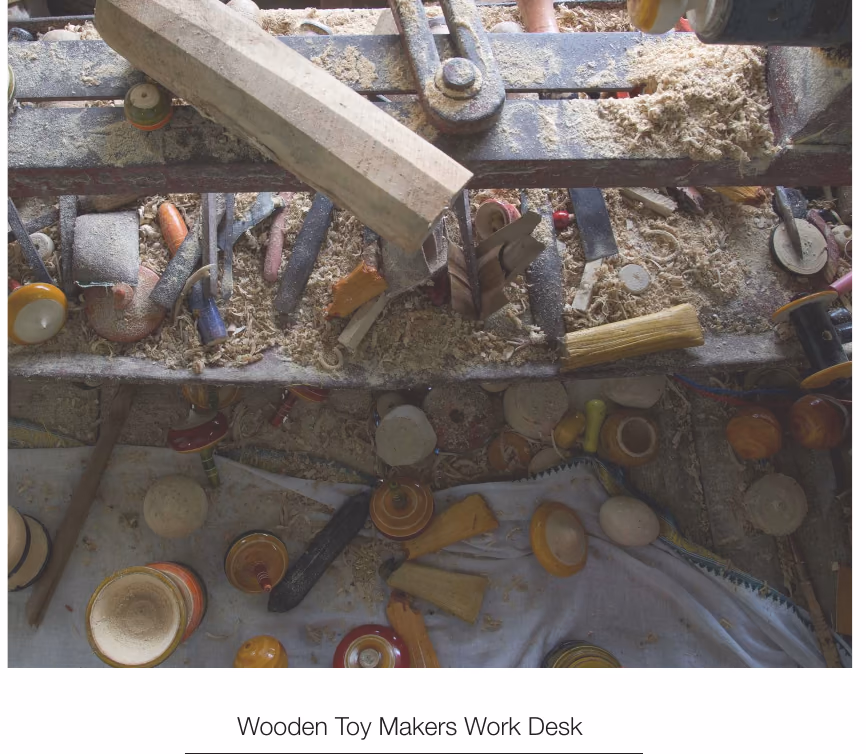 A wooden toy maker's work desk, covered in half-finished turned pieces, photographed on the site visit